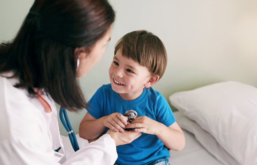 A provider listening to a young boy's chest with a stethoscope