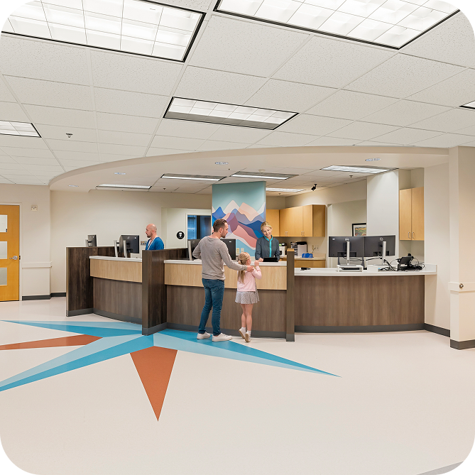 A parent and child checking in at a clinic front desk