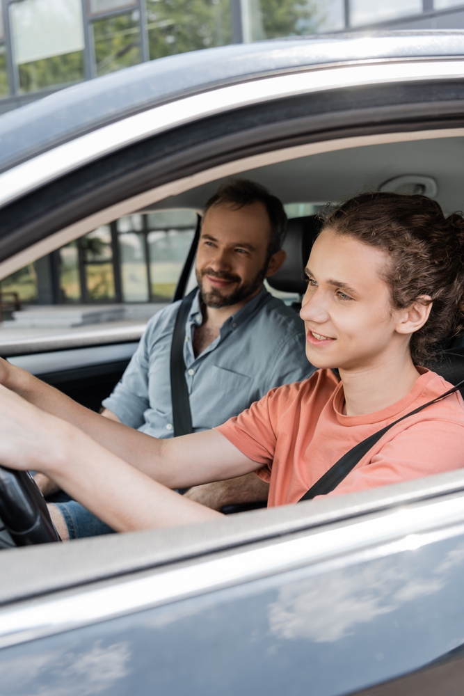 A teen driving a car while an adult sits in the passenger seat