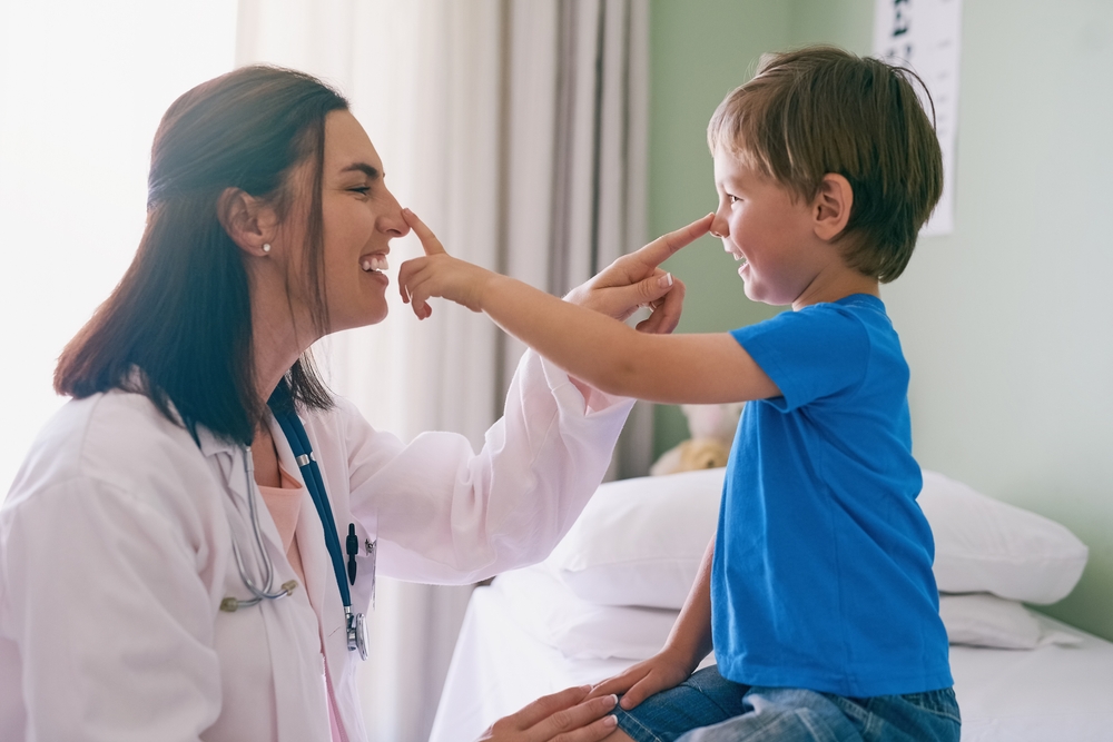 A provider playfully touching noses with a young boy during a checkup