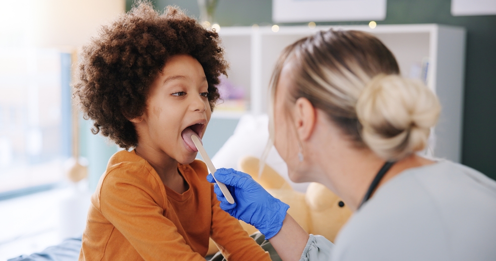 A provider checking a child's throat with a tongue depressor