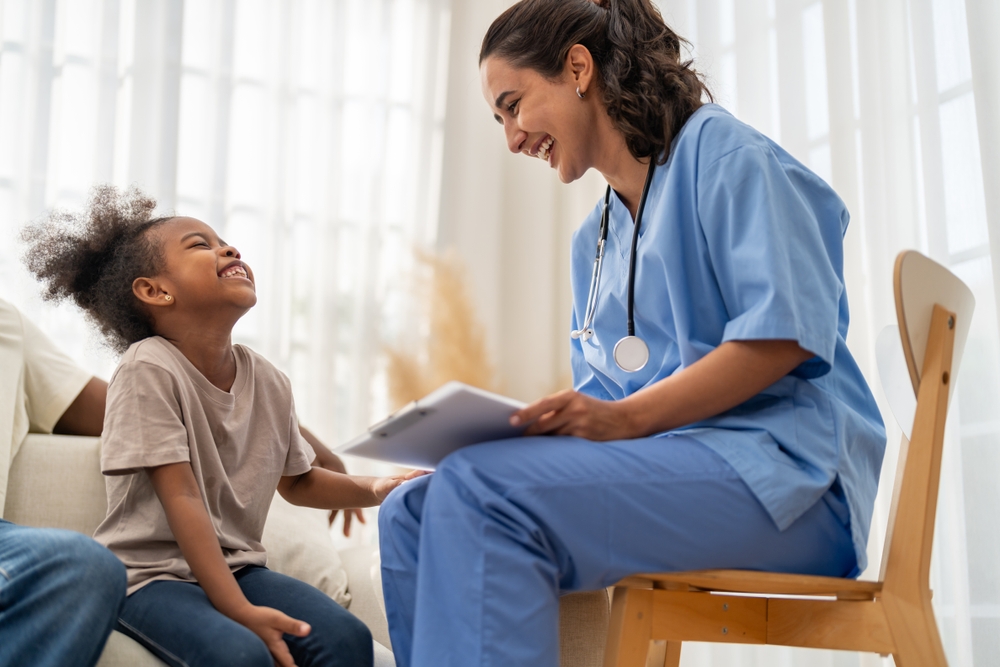 A provider laughing with a young girl during a visit