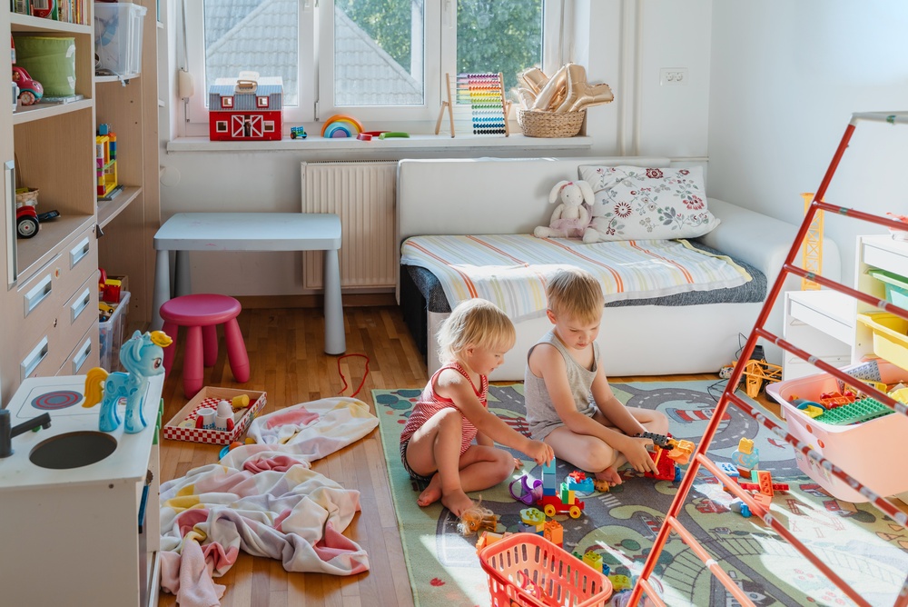 Two young children playing with toys together in a bedroom